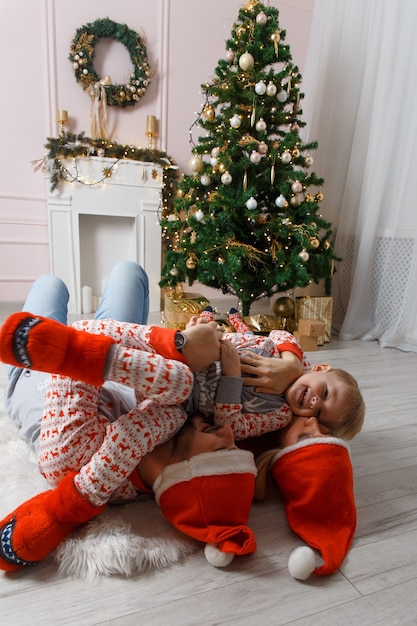 Gelukkige familie in de buurt van kerstboom plezier op de vloer.