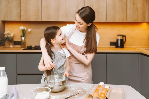 Gelukkige familie in de keuken moeder en dochter bereiden deeg bakken koekjes Pasen cake