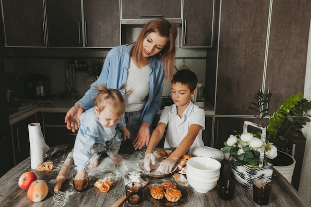 Gelukkige familie in de keuken. moeder en kinderen bereiden deeg en bakken een taart voor moederdag.