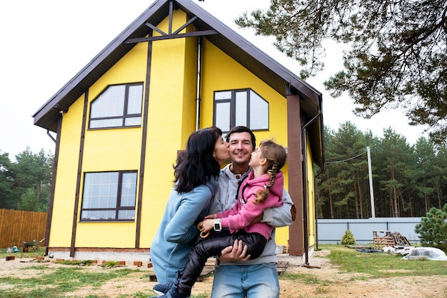 Gelukkige familie in de tuin van een onvoltooide huisaankoop van een huishypotheekverhuizingsconstructie