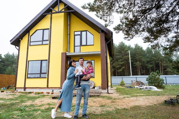 Gelukkige familie in de tuin van een onvoltooide huisaankoop van een huishypotheekverhuizingsconstructie