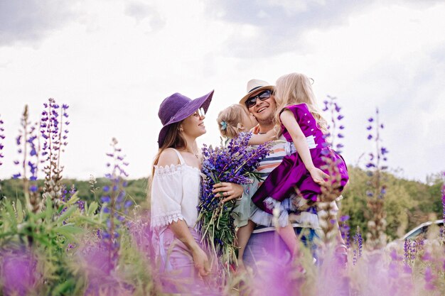 Gelukkige familie in een veld met lupines. Dochters kussen vader.