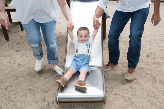 Gelukkige familie in park. Vader, moeder, zoon spelen glijbanen