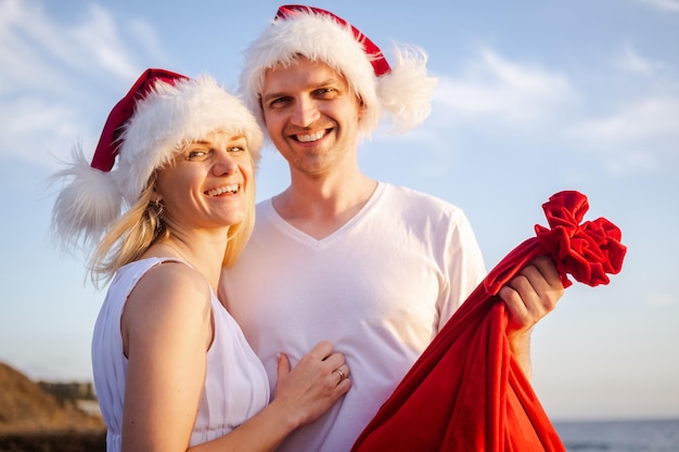 Gelukkige familie in Santa Claus-hoeden die Kerstmis vieren op het strand Glimlachende mensen die op wintertour naar warme landen reizen Nieuwjaar en kersttoeristen