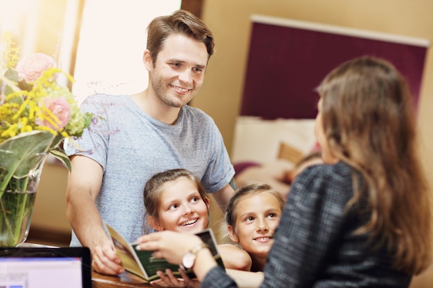 Gelukkige familie inchecken hotel bij receptie