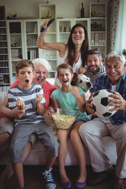 Gelukkige familie kijken naar voetbalwedstrijd op televisie in de woonkamer