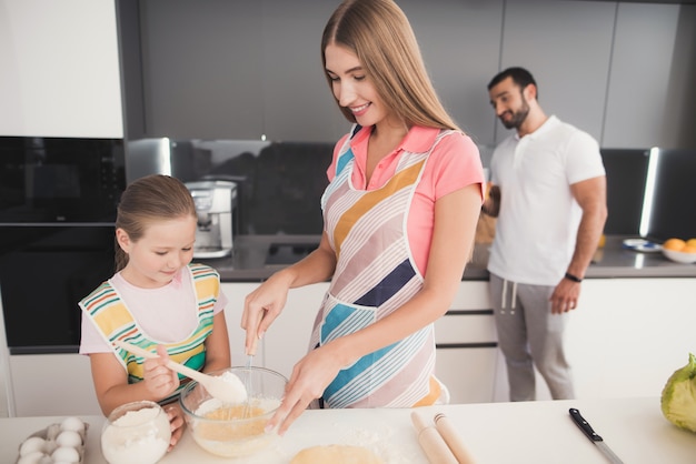 Gelukkige familie kookt met deeg in de keuken.