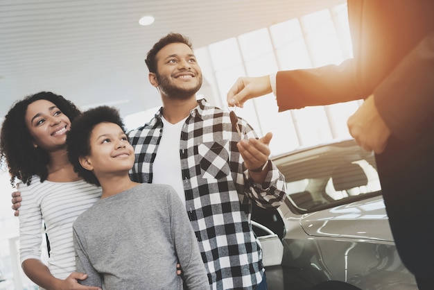 Gelukkige familie krijgt sleutels. Afro-mensen kopen auto.