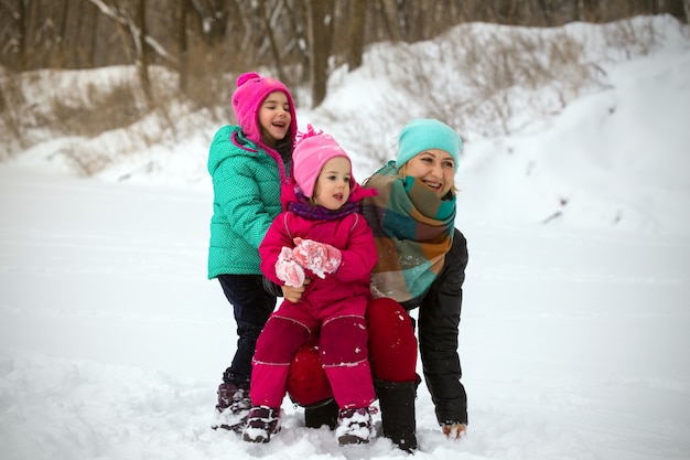 Gelukkige familie - lachende moeder en kleine dochters op de winterdag