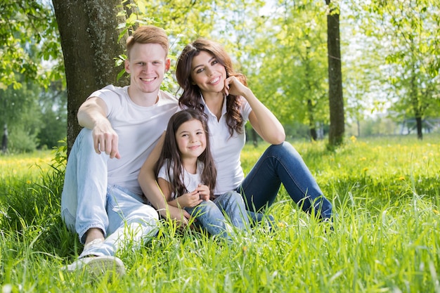 Gelukkige familie leunend op boom in park