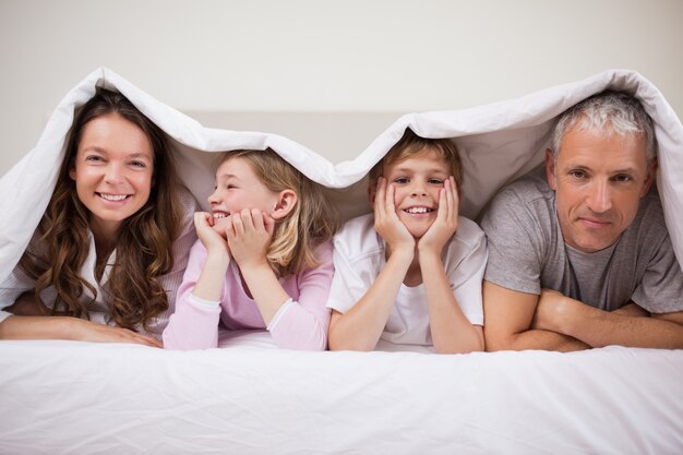 Gelukkige familie liggend onder een dekbed