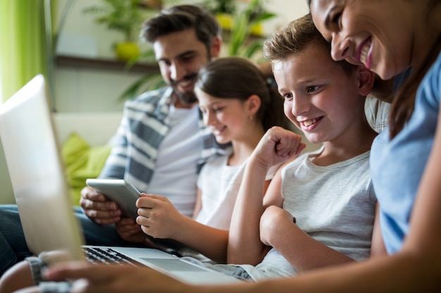 Gelukkige familie met behulp van laptop en digitale tablet in de woonkamer