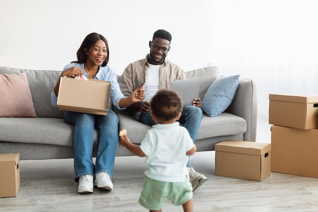 Gelukkige familie met behulp van laptop spelen met kind na verhuizing