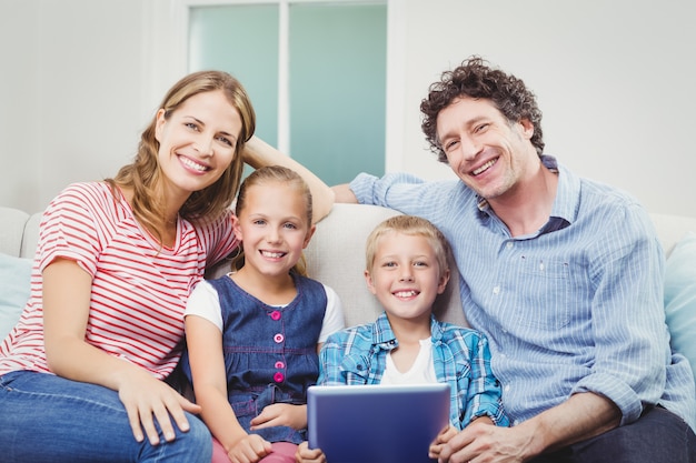 Gelukkige familie met digitale tabletzitting op bank