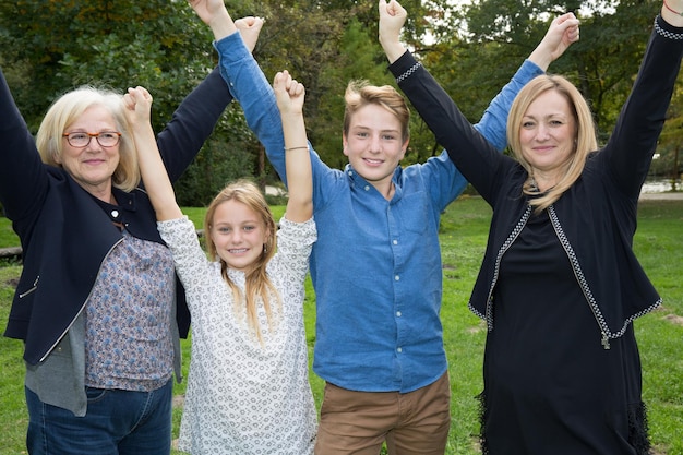 Foto gelukkige familie met handen omhoog op het gras