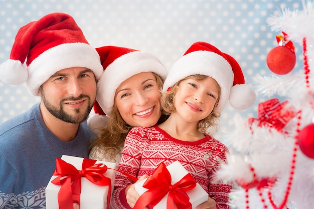 Gelukkige familie met kerstcadeaus in de buurt van de kerstboom. Kind, moeder en vader plezier thuis