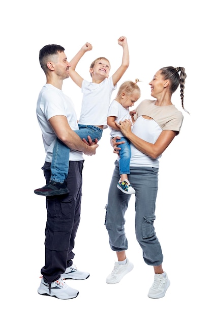 Gelukkige familie met kinderen moeder vader dochter en zoon in witte T-shirts en spijkerbroek knuffelen en lachen liefde en tederheid volle hoogte geïsoleerd op een witte achtergrond verticaal