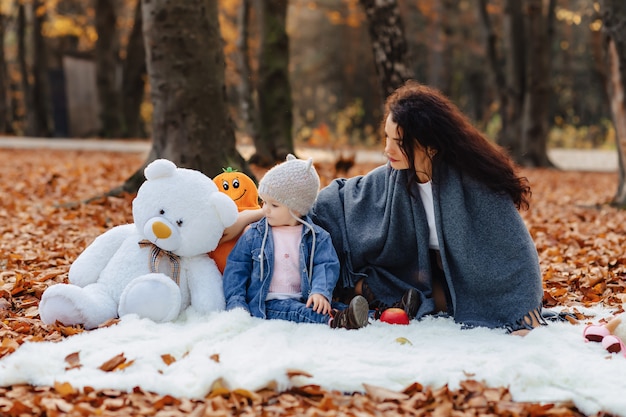 Gelukkige familie met klein schattig kind in park op geel blad met grote pompoen in de herfst
