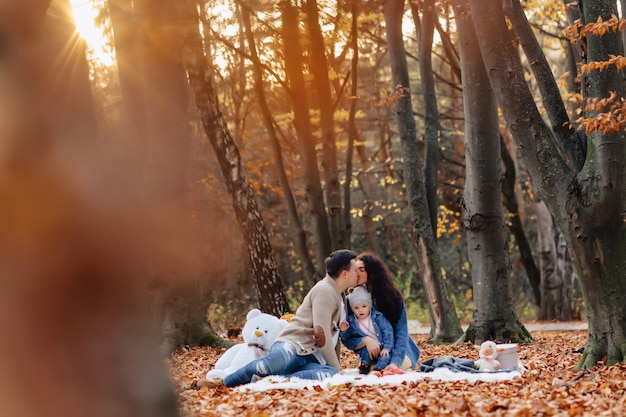 Gelukkige familie met klein schattig kind in park op geel blad met grote pompoen in de herfst