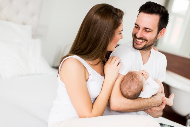 Gelukkige familie met pasgeboren baby op het bed in de kamer