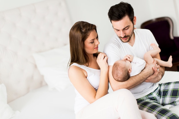 Gelukkige familie met pasgeboren baby op het bed in de kamer