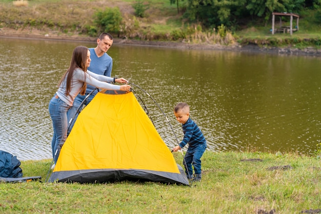 Gelukkige familie met zoontje opgezet camping tent. gelukkige jeugd, kampeertrip met ouders.