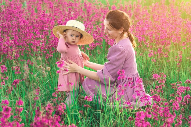 Gelukkige familie moeder en baby dochter knuffelen op weide met bloeiende paarse bloemen