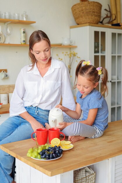 gelukkige familie moeder en dochter drinken thee in de keuken familie ontbijt