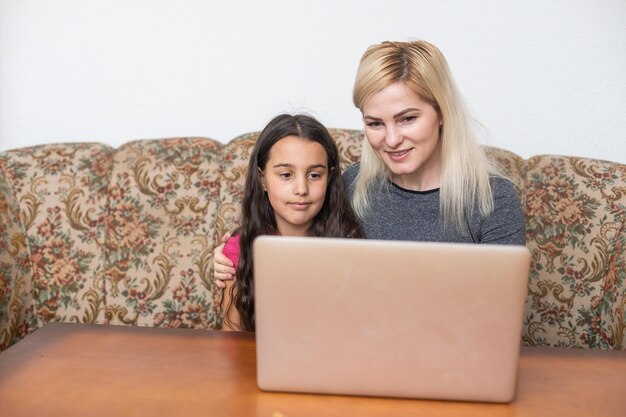 Gelukkige familie Moeder en dochter kijken naar video-entertainment met laptopcomputertechnologie de woonkamer geniet van het leven thuis concept