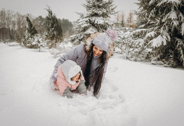 Gelukkige familie moeder en dochter veel plezier met spelen op winterwandeling buiten. familie in winterbos