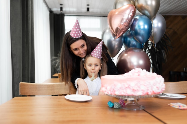 Gelukkige familie moeder en dochter vieren een verjaardag of jubileum Mooie taart en ballonnen