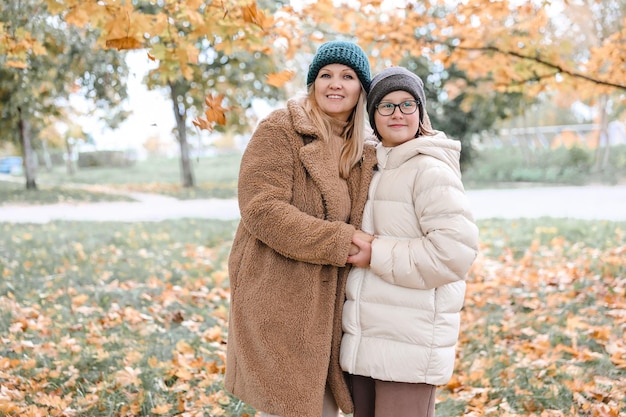 Gelukkige familie, moeder en dochter zijn in het herfstpark. Ze poseren lachend, spelend en plezier makend Felgele bomen