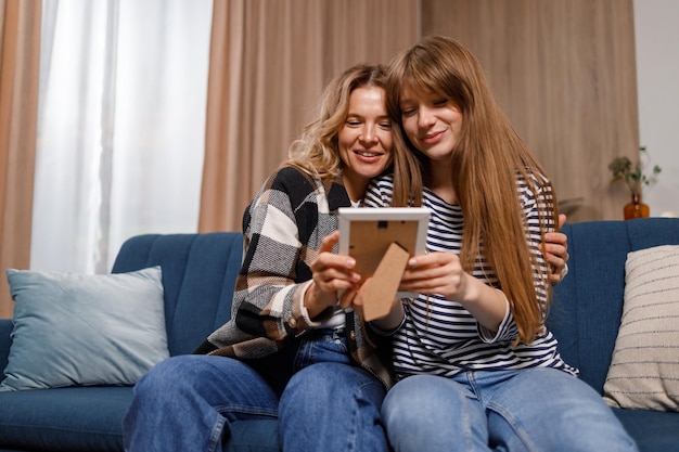 Gelukkige familie moeder en dochter zittend op de bank en kijken naar frame foto