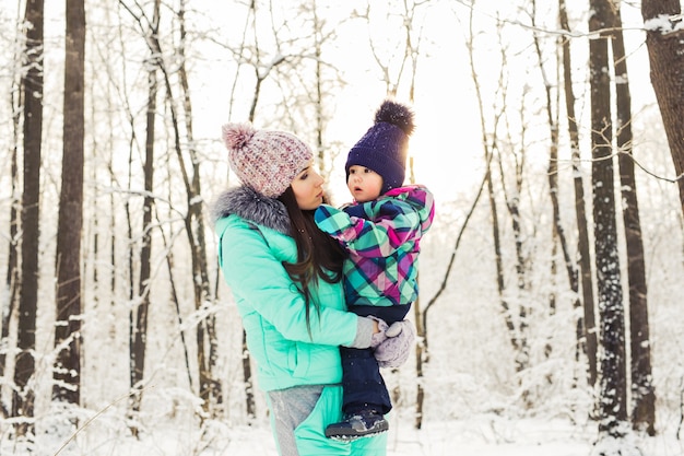 Gelukkige familie moeder en kind baby dochter op een winterwandeling in het bos.