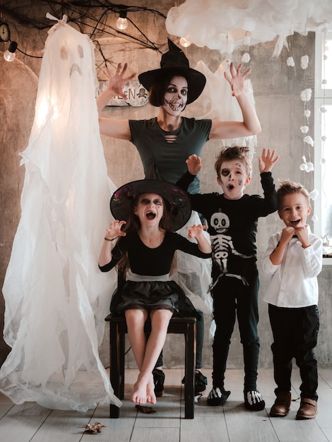 Gelukkige familie moeder en kinderen in kostuums en make-up op de halloween-viering op de achtergrond van het ghost-landschap, carnavalfeest