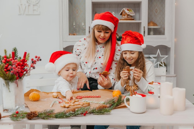 Gelukkige familie, moeder en kinderen, zoon en dochter bakken peperkoekkoekjes voor Kerstmis in de keuken.