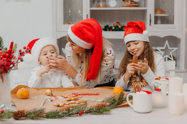 Gelukkige familie, moeder en kinderen, zoon en dochter bakken peperkoekkoekjes voor Kerstmis in de keuken.