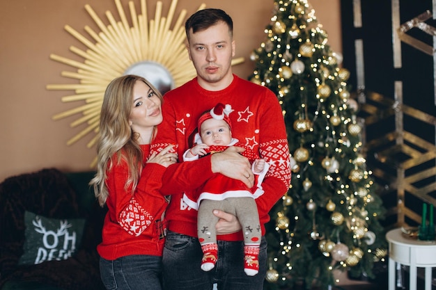 Gelukkige familie moeder vader en dochtertje in rode traditionele kerstkleren tijd samen doorbrengen in de buurt van de kopieerruimte van de kerstboom