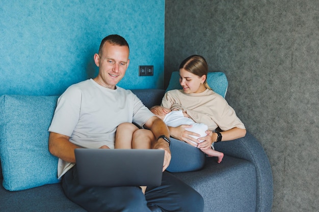 Gelukkige familie moeder vader en schattige baby zoon hebben plezier met laptop thuis Jonge ouders en grappige peuter kind jongen die levensstijl tijd doorbrengen bij de computer zitten op de bank