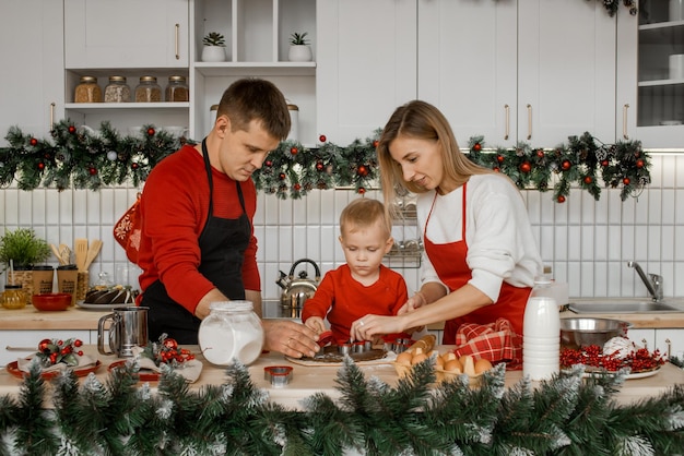 Gelukkige familie, moeder, vader en zoontje zijn geconcentreerd op het koken van kerstkoekjes