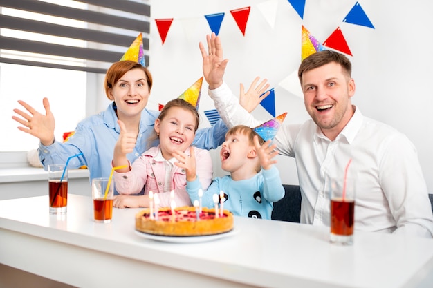 Foto gelukkige familie, moeder, vader, zoon, dochter vieren een verjaardagsfeestje voor kinderen met de taart.