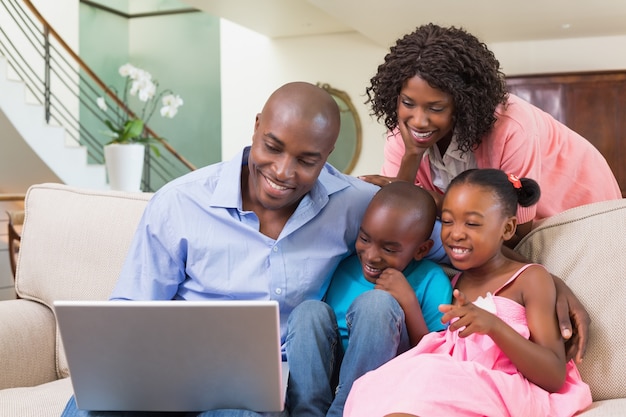 Gelukkige familie ontspannen op de bank met behulp van laptop