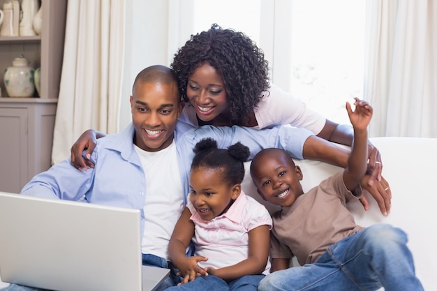 Gelukkige familie op de bank die samen laptop met behulp van