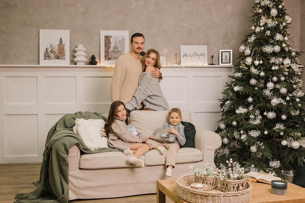 Gelukkige familie op de bank in de kamer tegen de achtergrond van de kerstboom