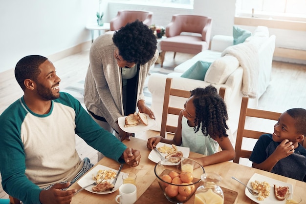 Gelukkige familie ouders en kinderen met eten voor het ontbijt in het huis met het serveren van binding en top uitzicht in de eetkamer zwarte mensen moeder en vader met kinderen in de ochtend met eieren en brood voor voeding