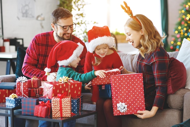 Gelukkige familie ouders en kinderen openen cadeautjes op kerstochtend