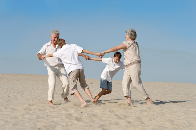 Gelukkige familie plezier op blote voeten in het zand in de zomer
