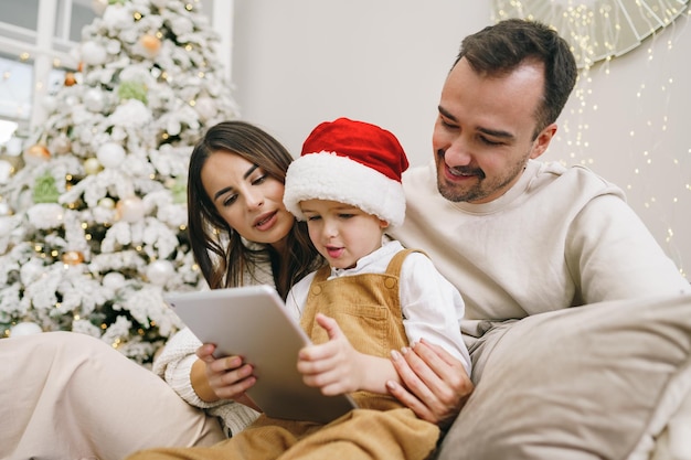 Gelukkige familie plezier op digitale tablet in bed met kerst