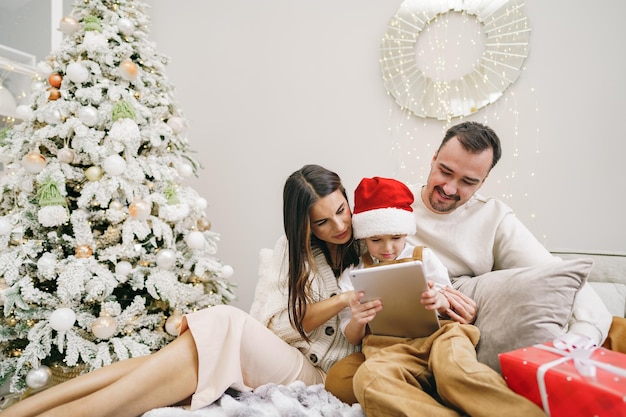 Gelukkige familie plezier op digitale tablet in bed met kerst