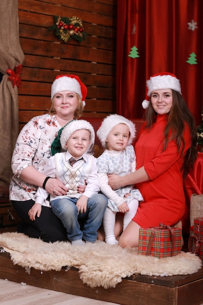 Gelukkige familie poseren voor foto met Kerstmis. grootmoeder en moeder met twee kinderen in santahoeden.